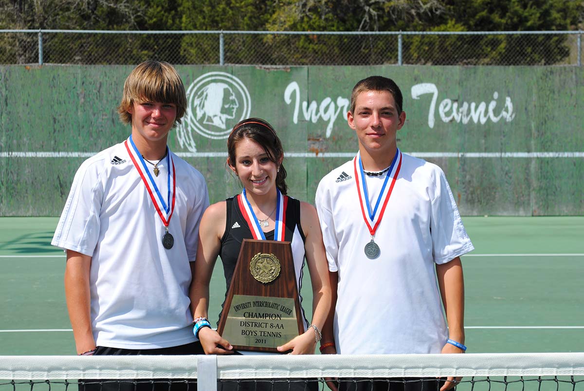 Ashton (left) at the Ingram tennis courts with two teammates, medals around their necks, holding the district champions plaque