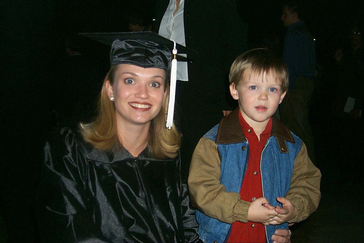 Ashton's Aunt Cayce in graduation cap and gown with her arm around young Ashton in a red shirt and denim vest