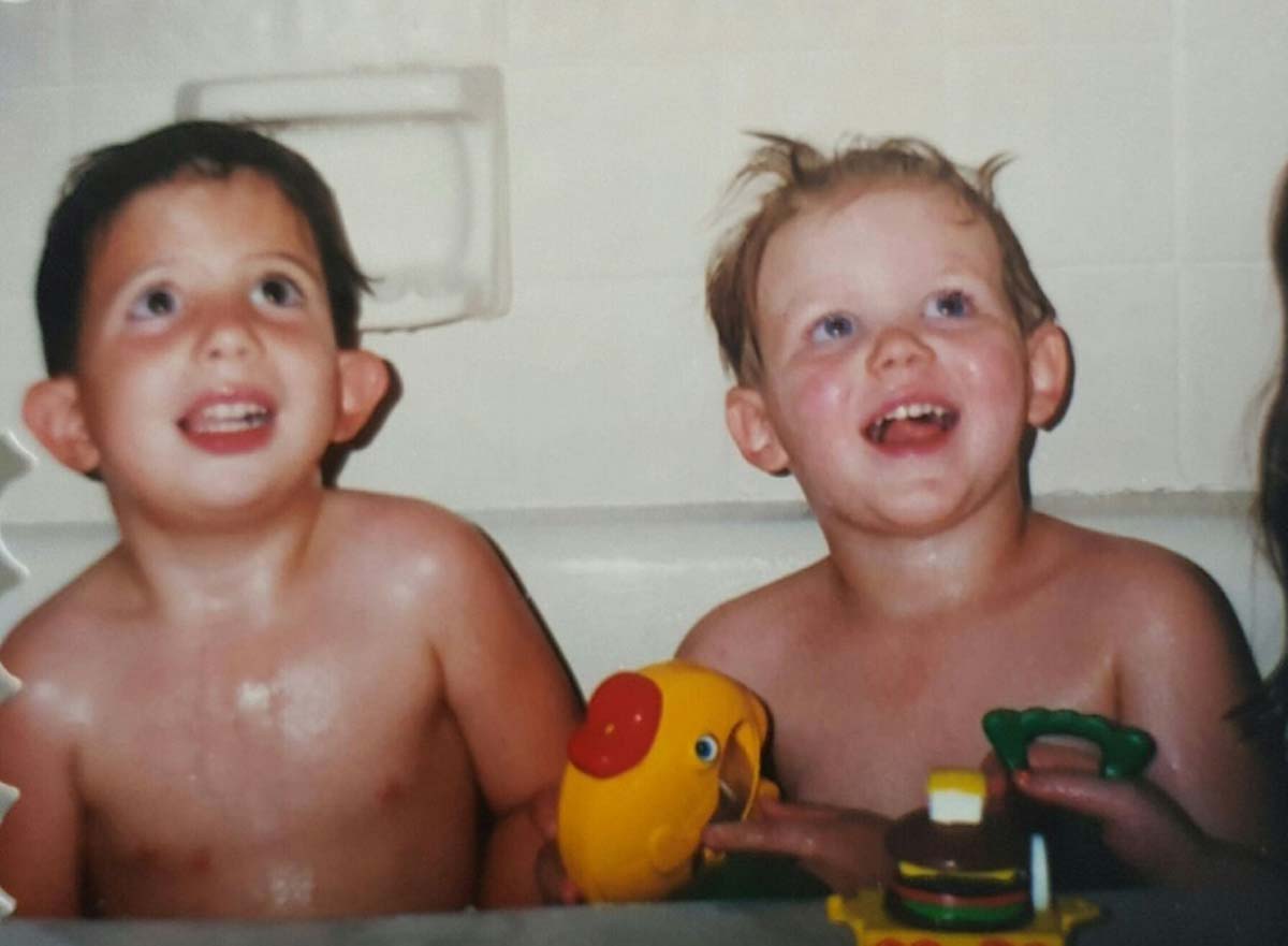 Ashton (right) laughing in the bathtub with a rubber duck on the ledge