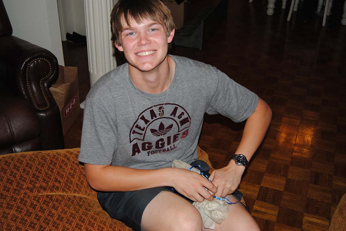 Ashton with a huge grin in his Texas A&M Aggies tee, a small puppy in his lap