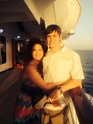 Ashton on a ship's deck at sunset with his mom, golden light