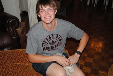 Ashton with a huge grin in his Texas A&M Aggies tee, a small puppy in his lap